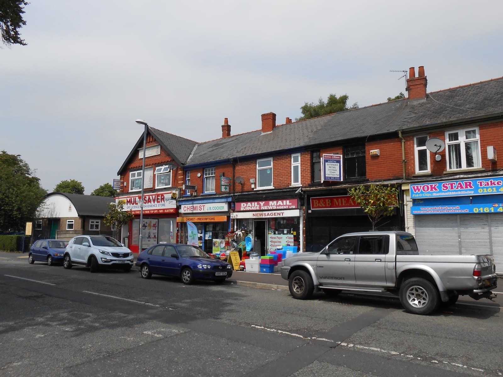 A row of shops on a wet street, the Sifters sign on the right beside a set of traffic lights