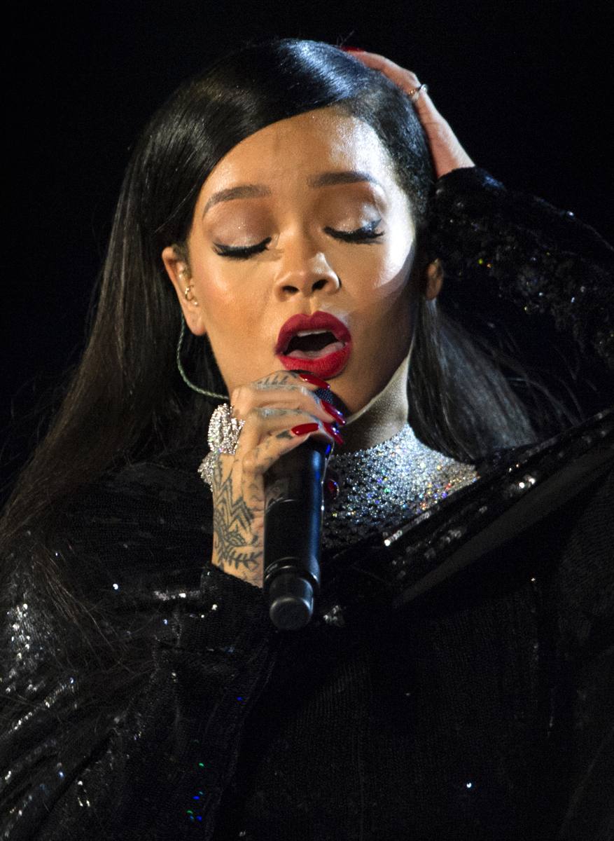 Rihanna singing into a microphone on an outdoor stage in 2014