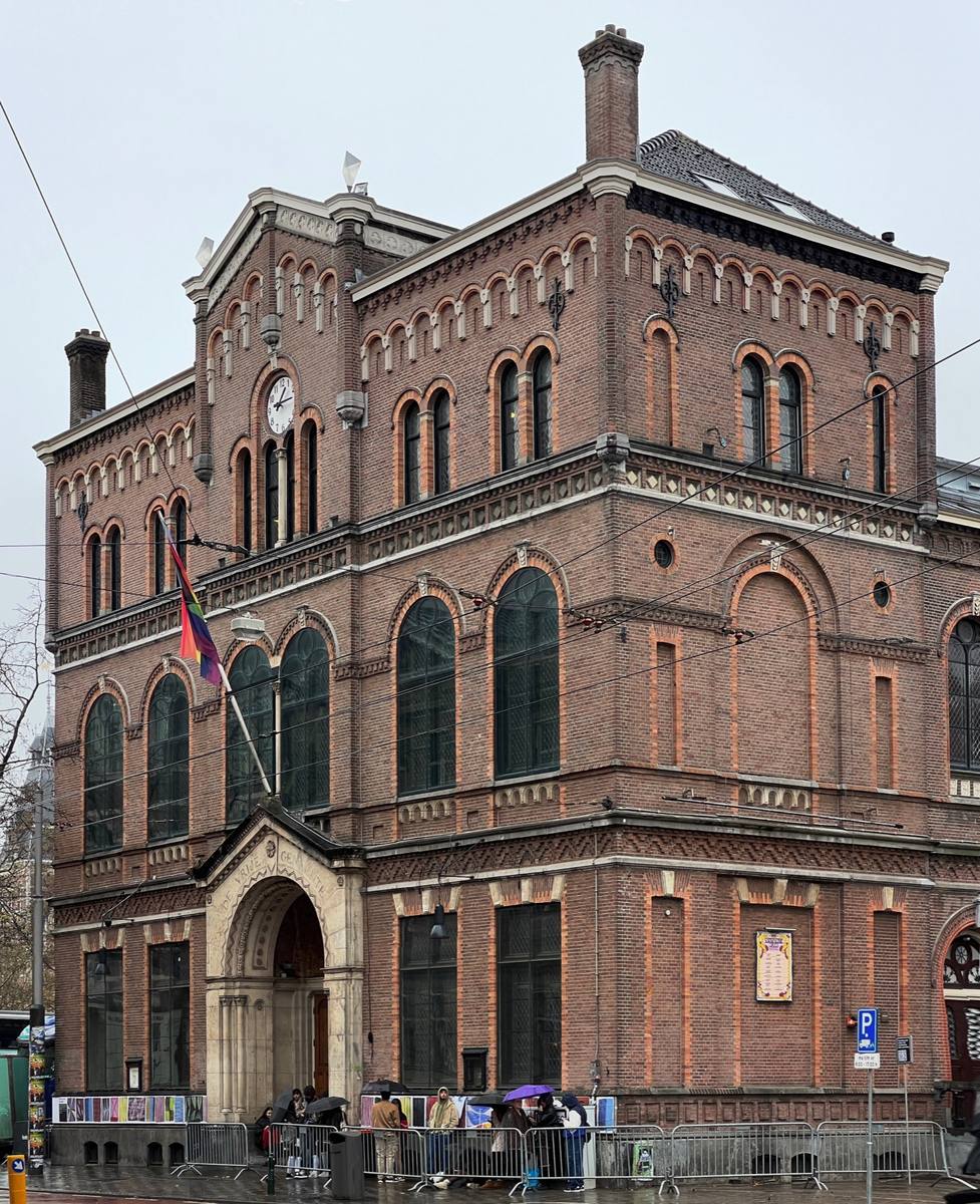 A tall red-brick nineteenth-century hall with arched windows and a gabled top