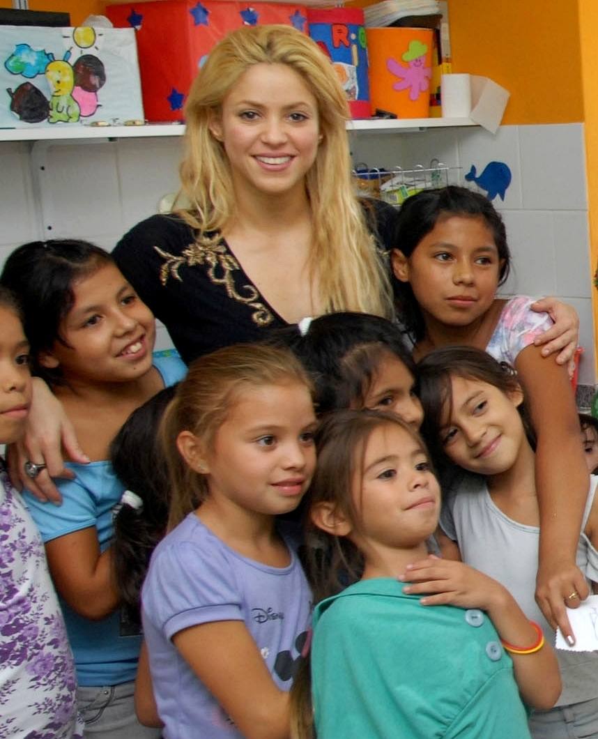 Shakira crouching with small children in 2011