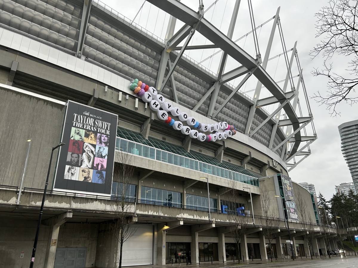 A huge beaded bracelet strung across the steel side of BC Place stadium beside a tour poster