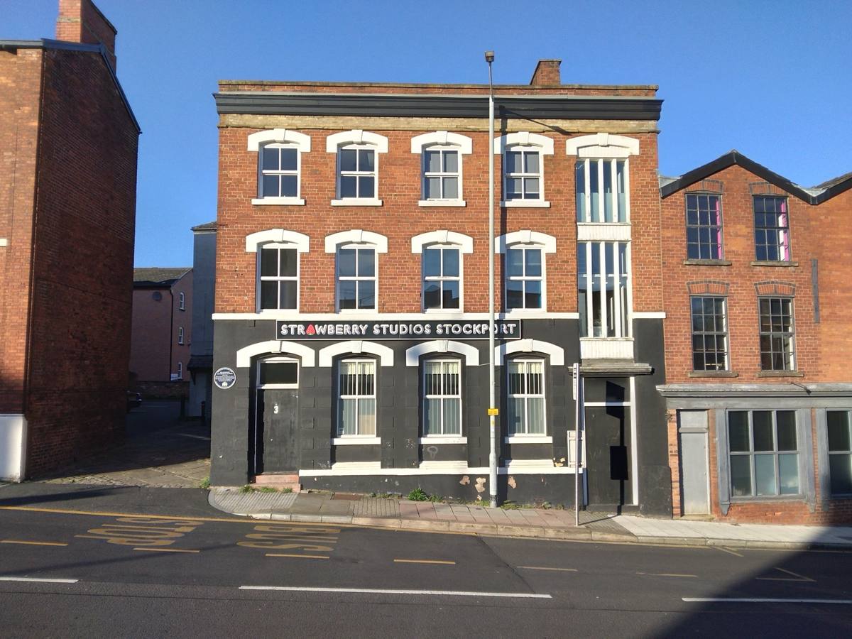 A three-storey brick building on a street corner, the studio’s name painted above the door