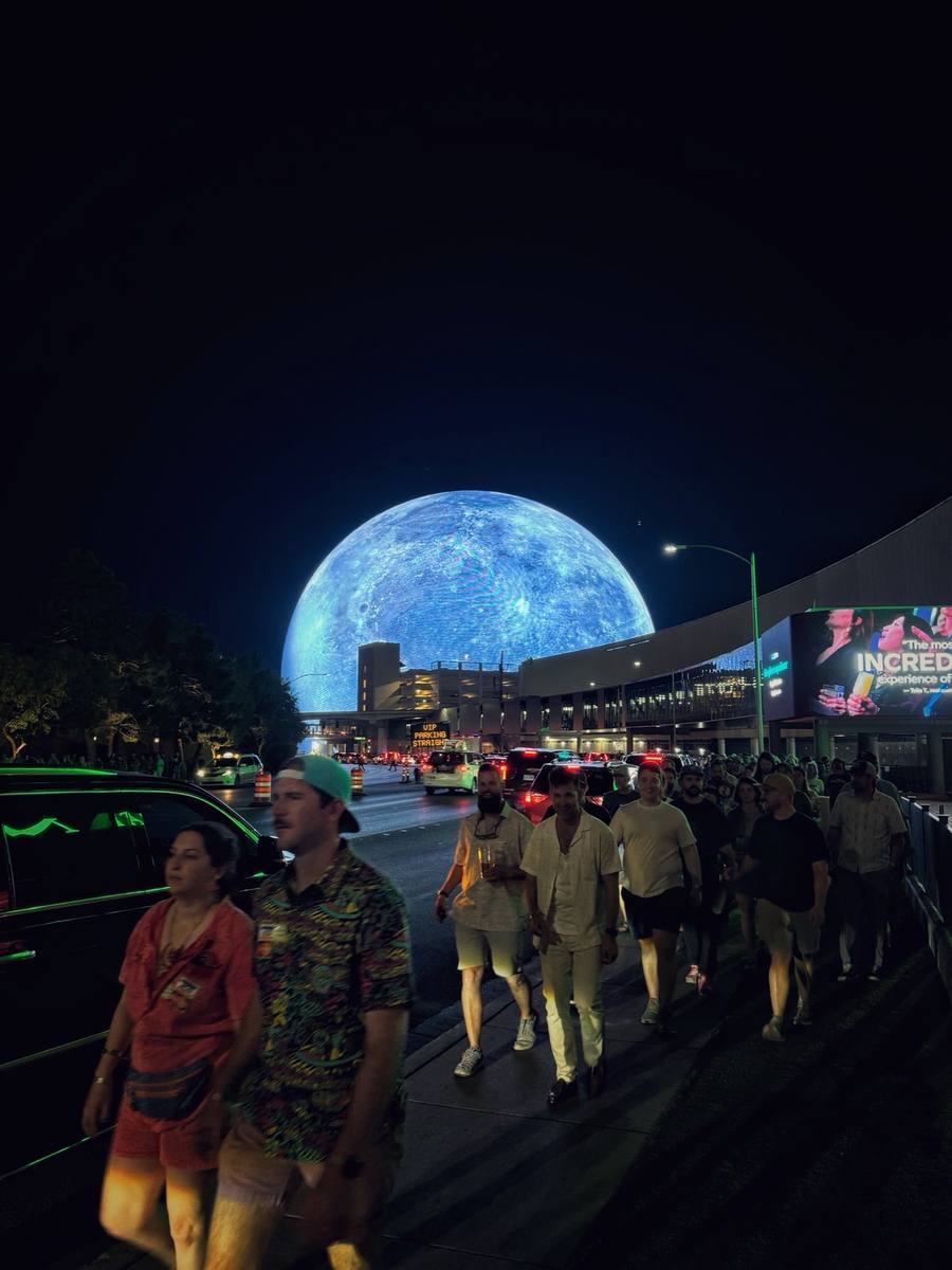 A huge glowing blue globe at the end of a busy night-time street