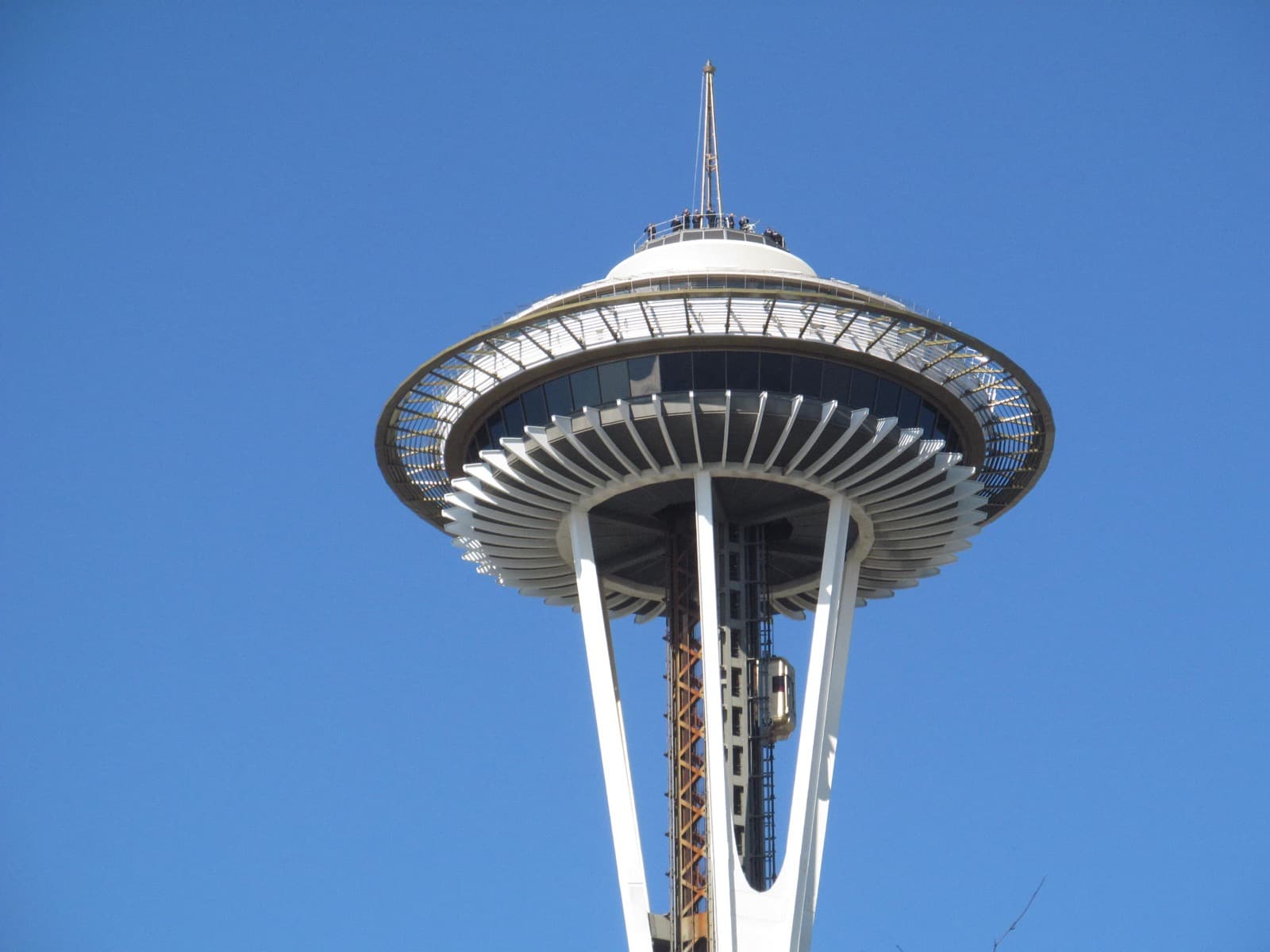 The disc-shaped top of the Space Needle against a clear blue sky