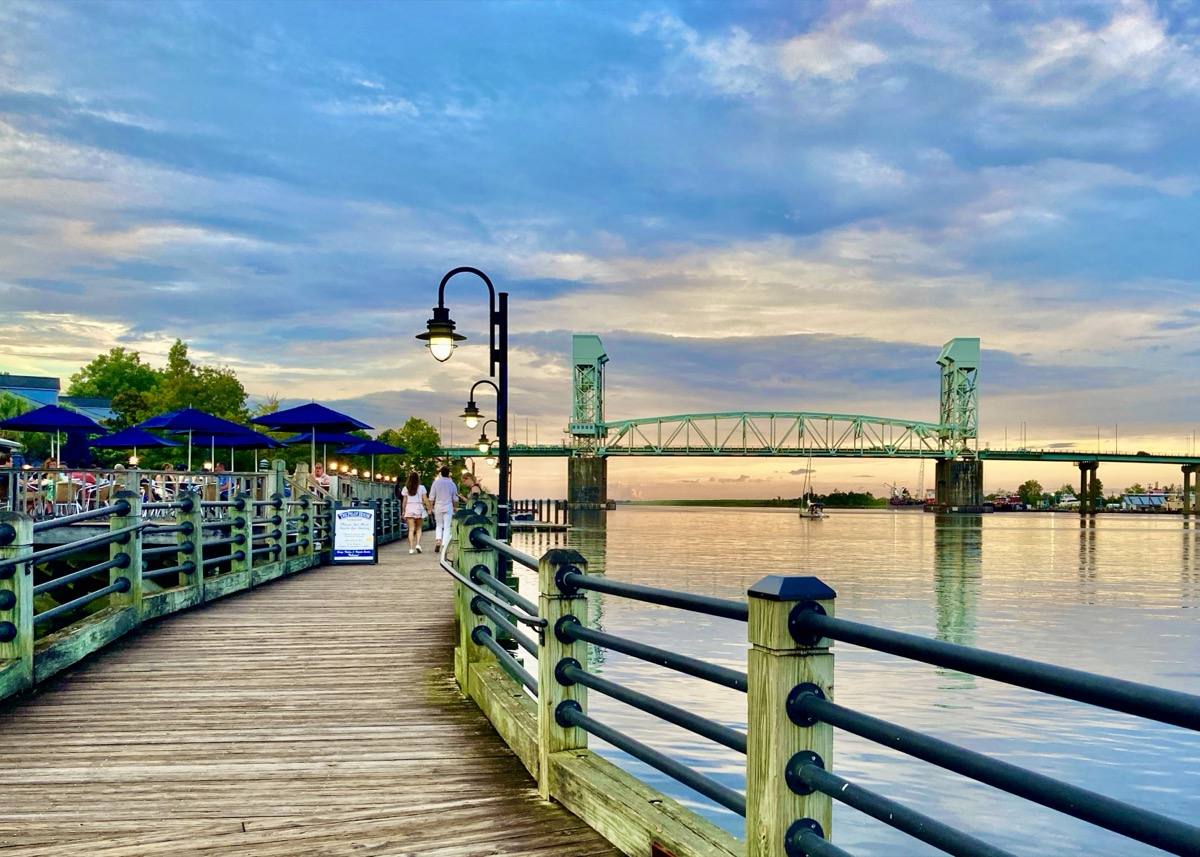 The Wilmington Riverwalk at sunset with the river and a lift bridge in the distance