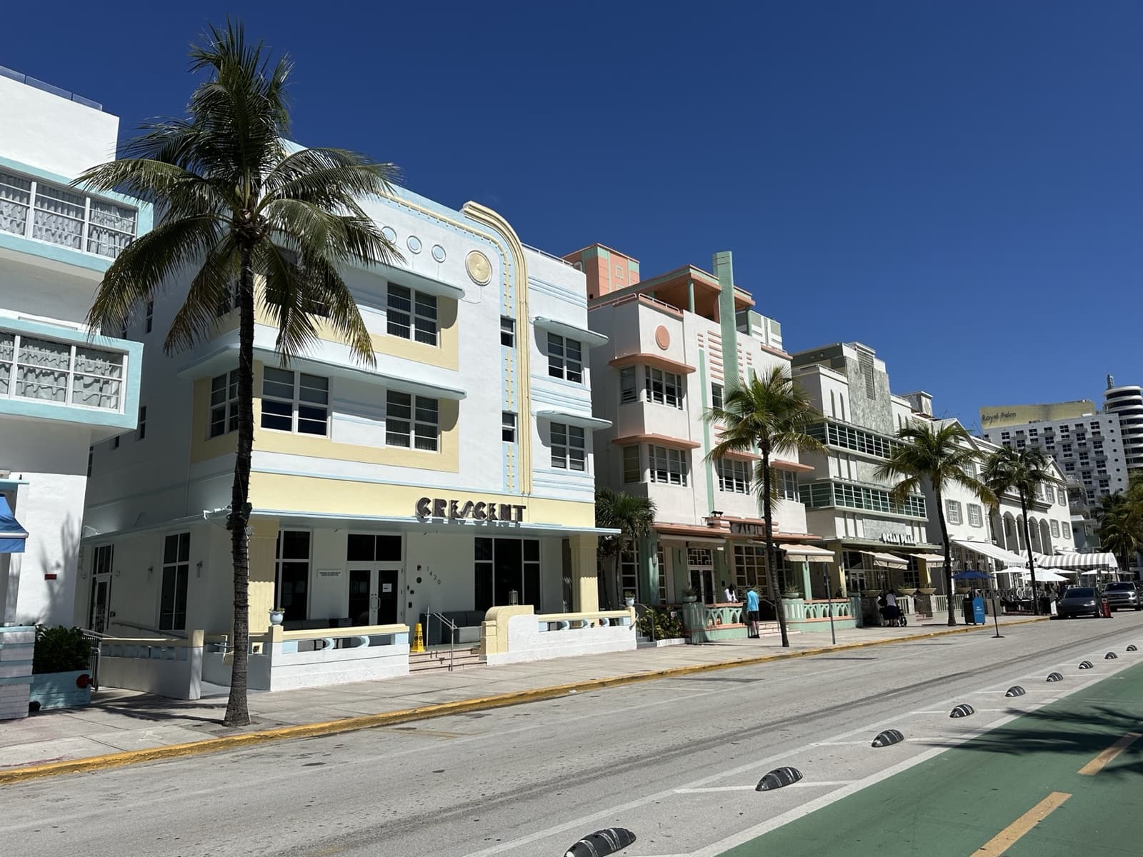 Pastel Art Deco hotels along Ocean Drive under a blue sky, the Crescent sign on the left