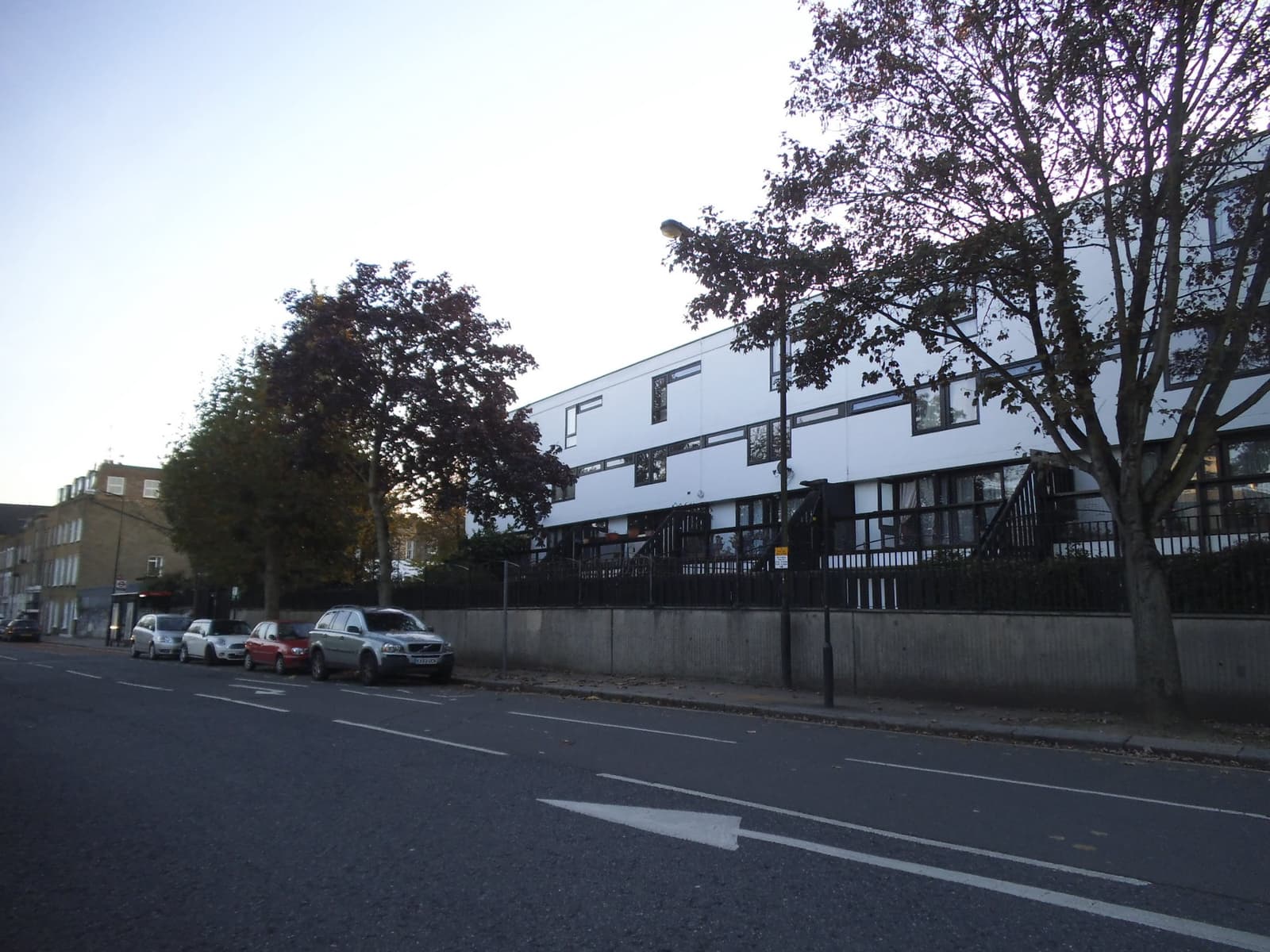 Blocks of flats behind trees along a broad north London road