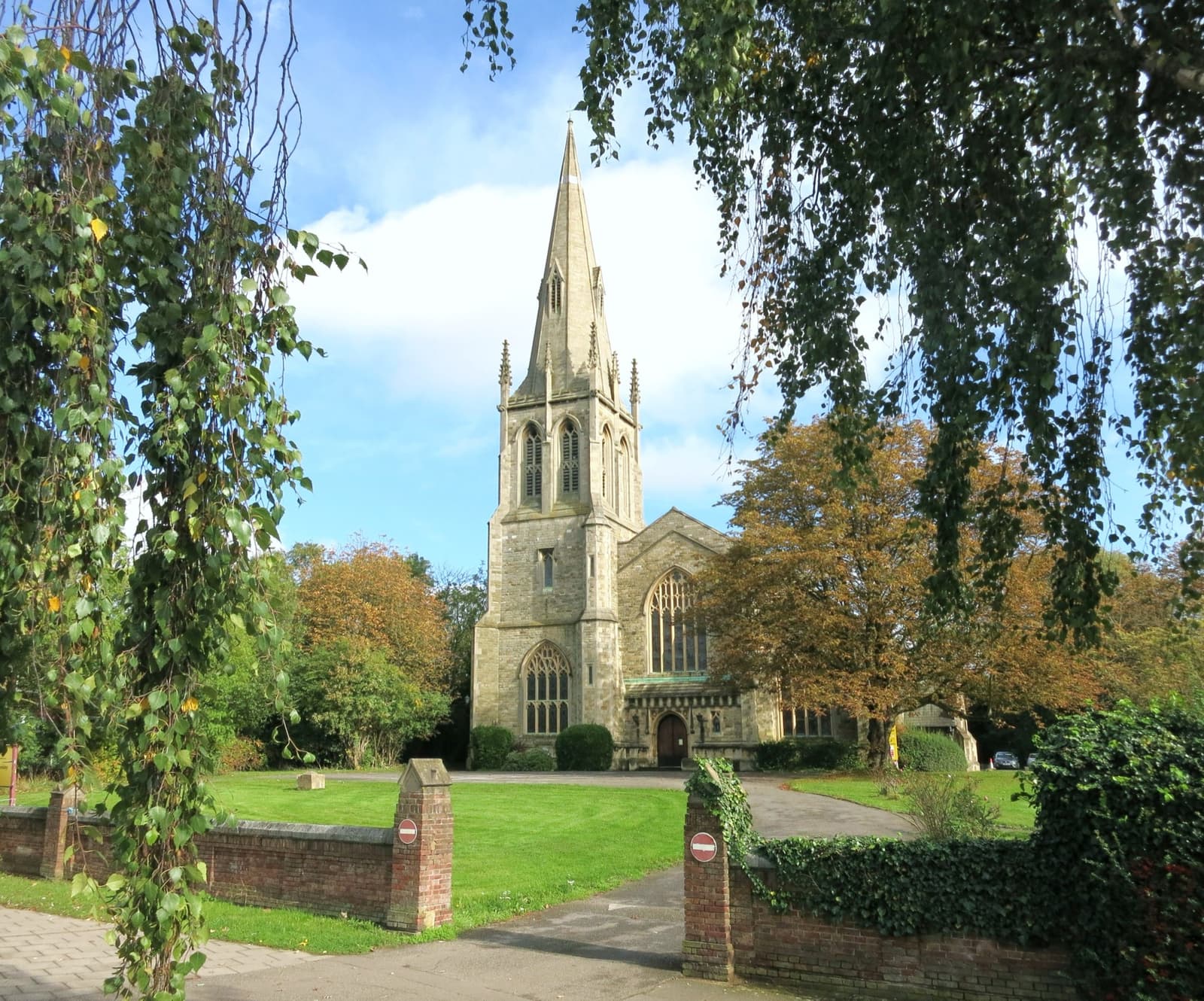 A large Victorian Gothic church with a slender spire behind a churchyard