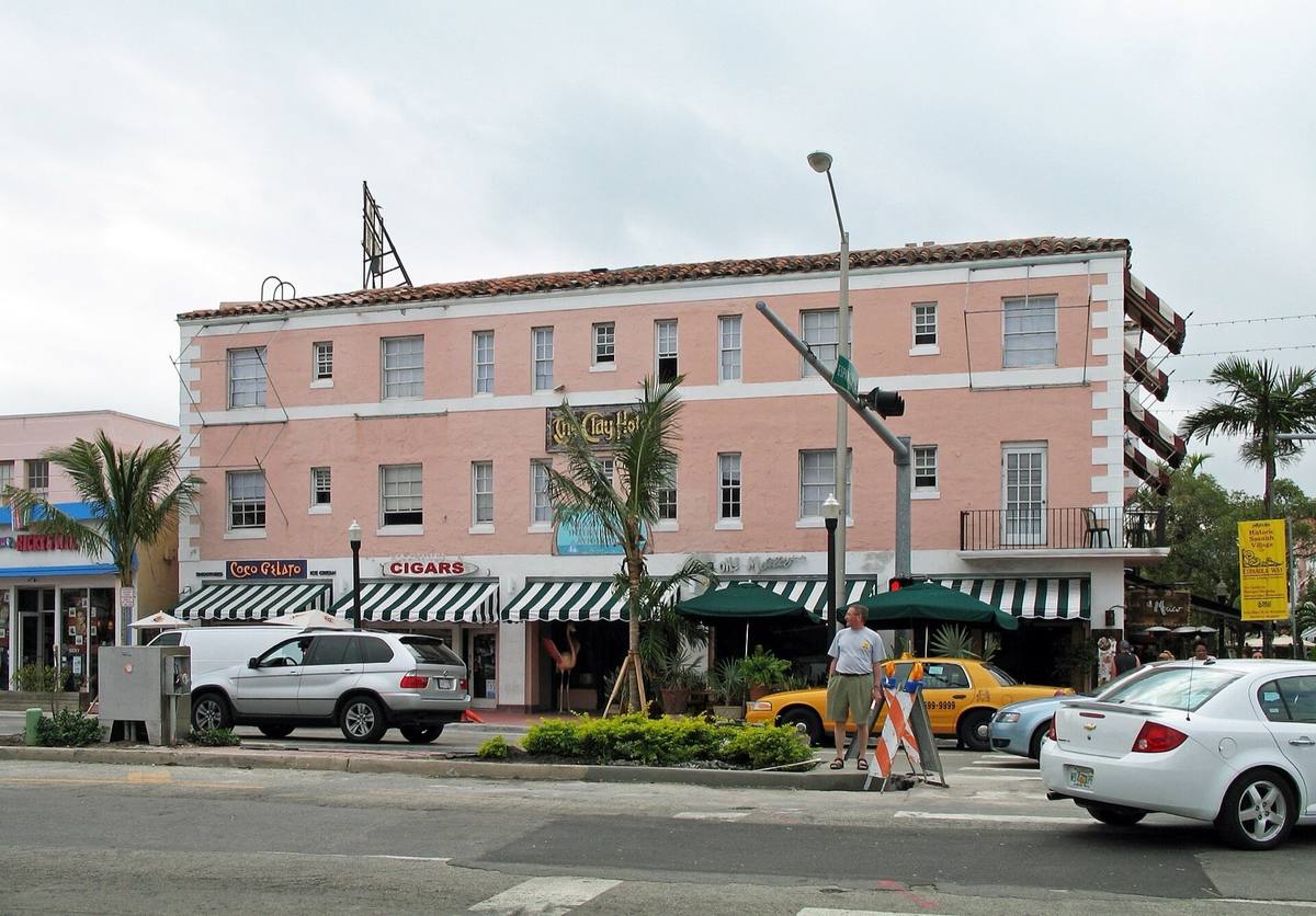 A pink three-storey hotel with striped awnings on a street corner