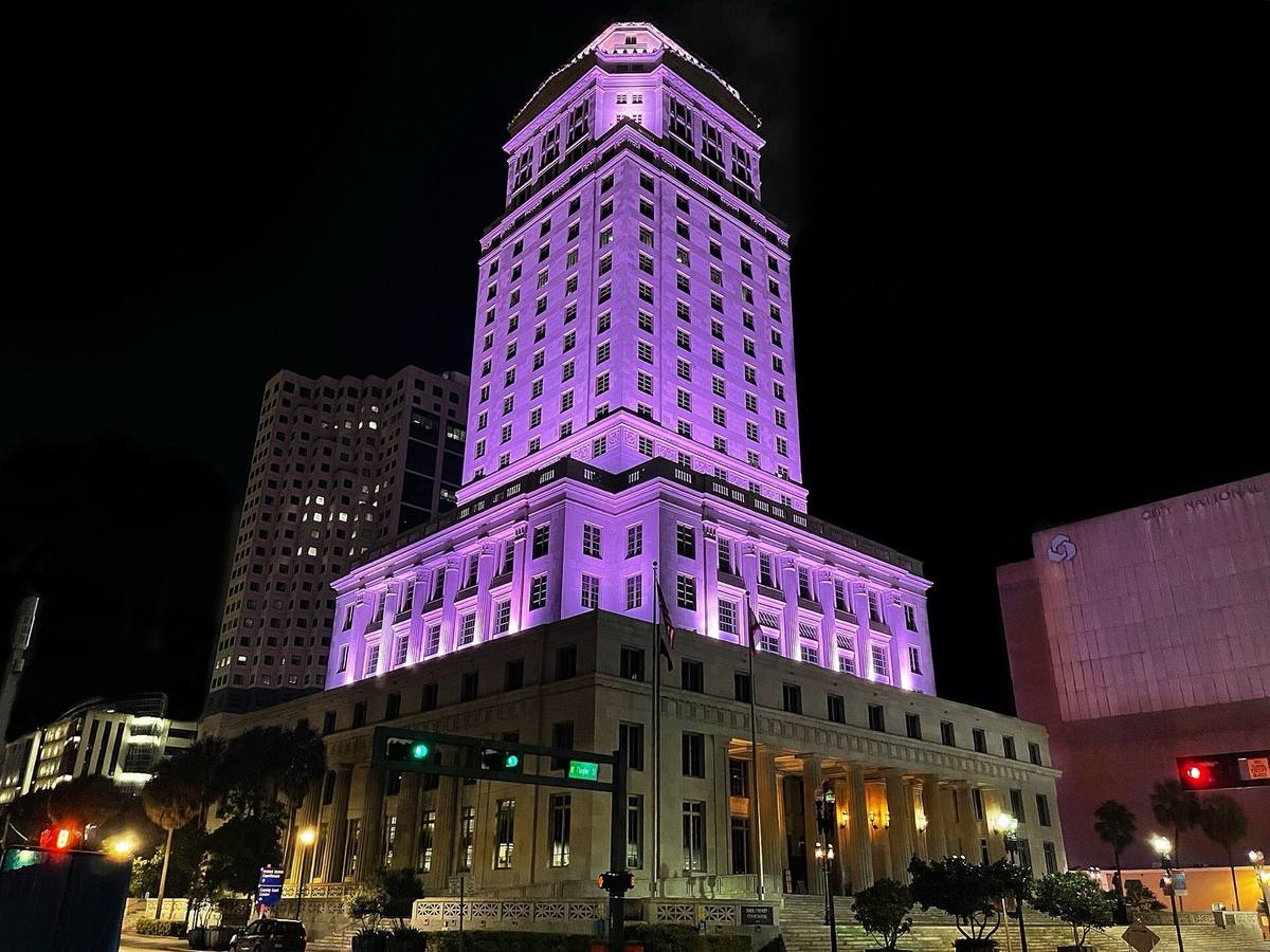 A stepped neoclassical tower lit purple at night