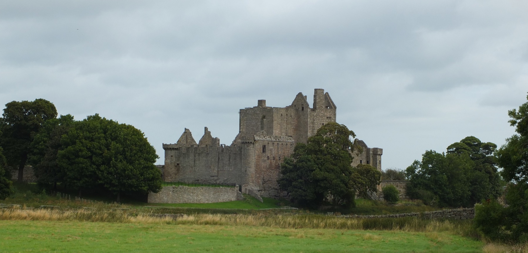The grey ruin of Craigmillar Castle on a green rise