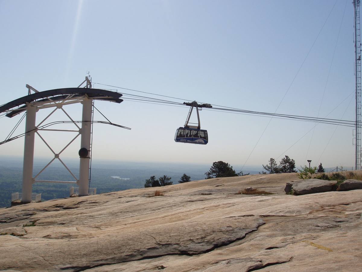 A cable car on its wire above the bare granite top of Stone Mountain