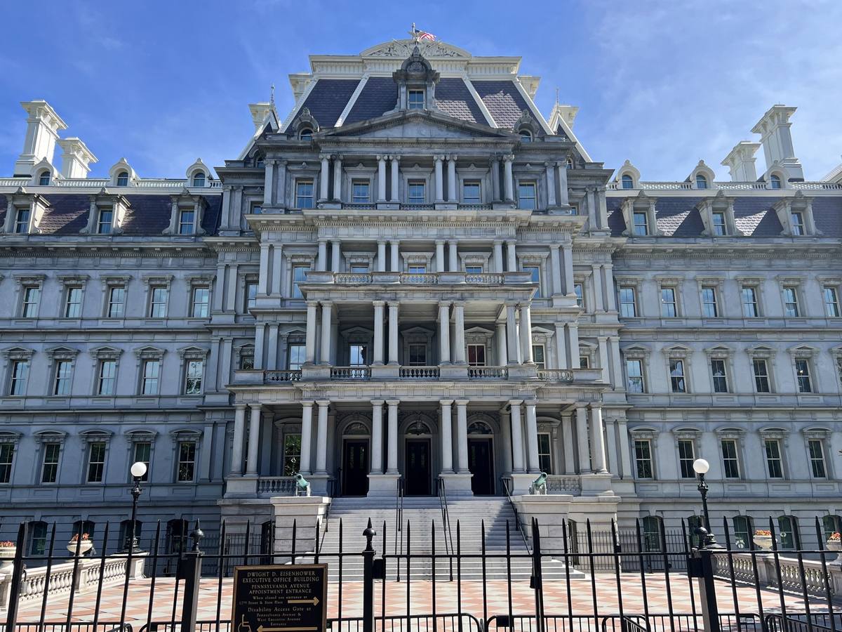 An ornate grey Second Empire facade behind a black railing