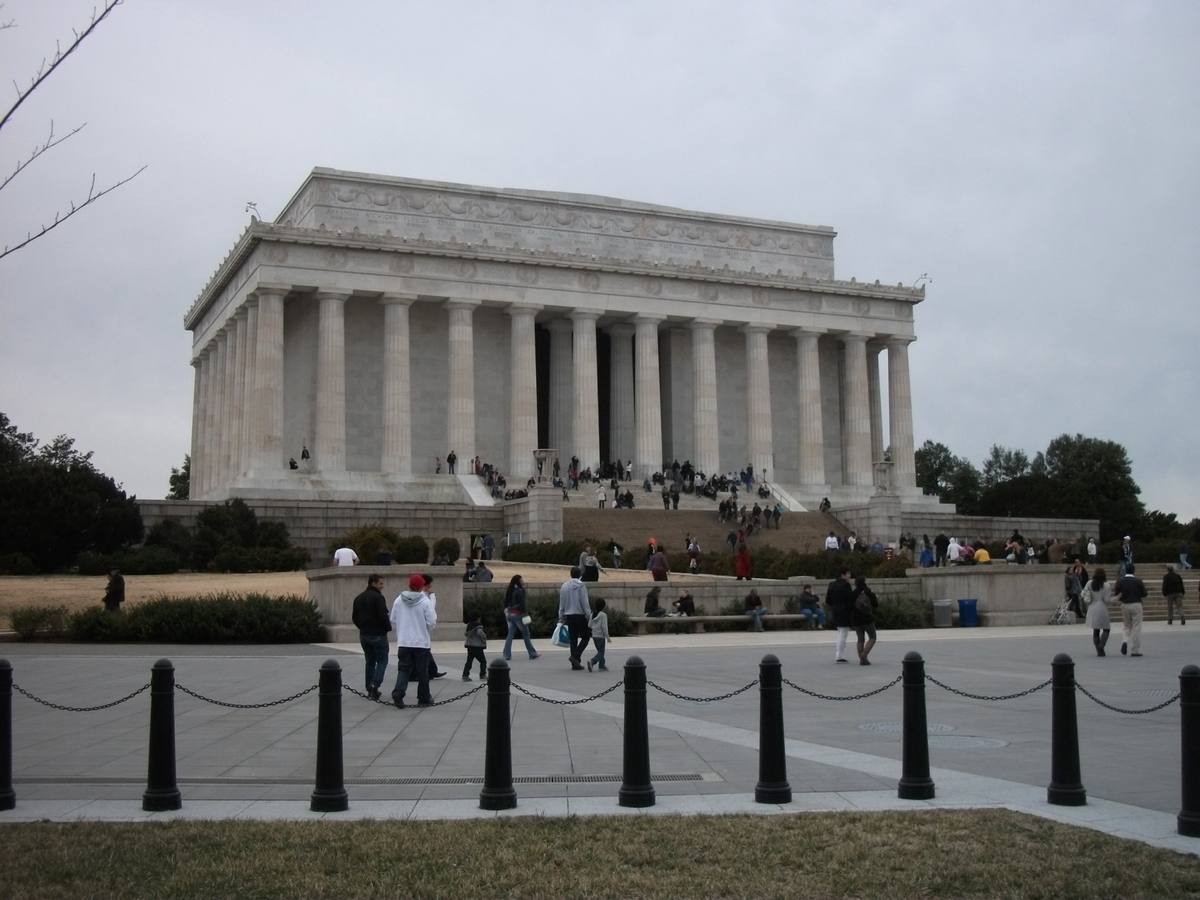 A white colonnaded temple with visitors on the steps