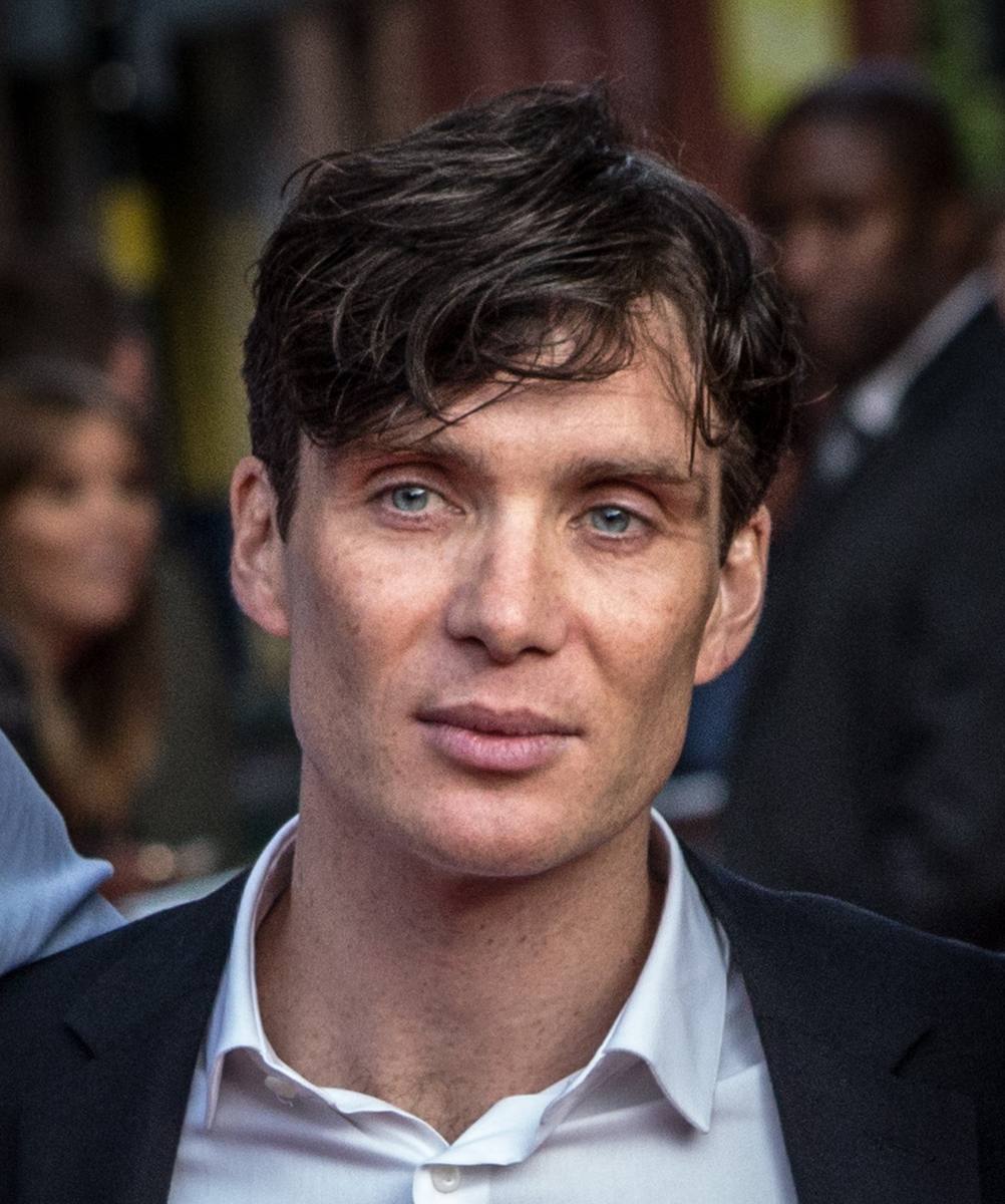 Cillian Murphy with a short-back-and-sides haircut, open white collar and dark jacket, at an evening premiere