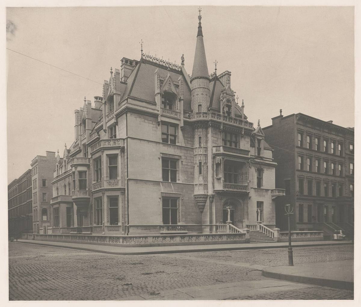 A pale stone French Gothic mansion with steep roofs and turrets on a corner of Fifth Avenue