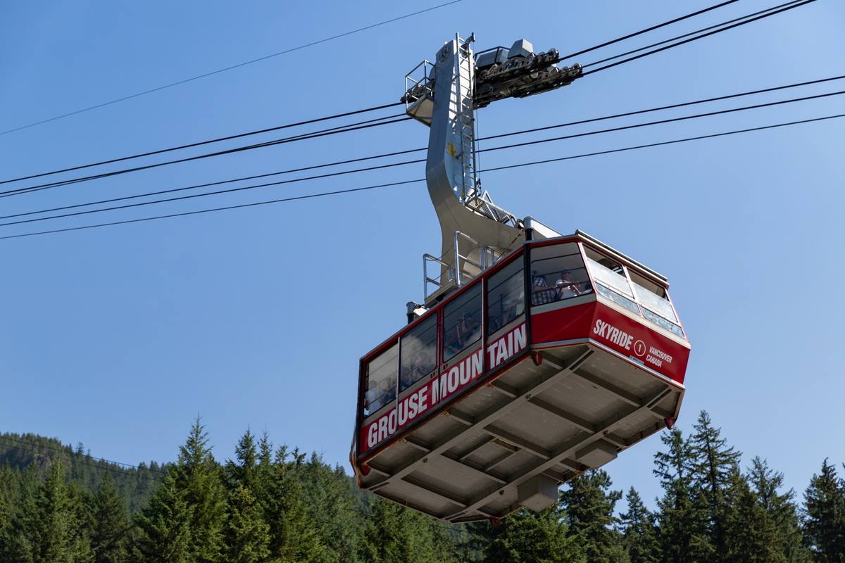 A red aerial tram car above a forested slope on Grouse Mountain