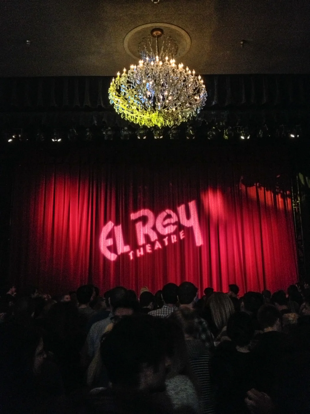 The El Rey stage with red curtains and a chandelier above.