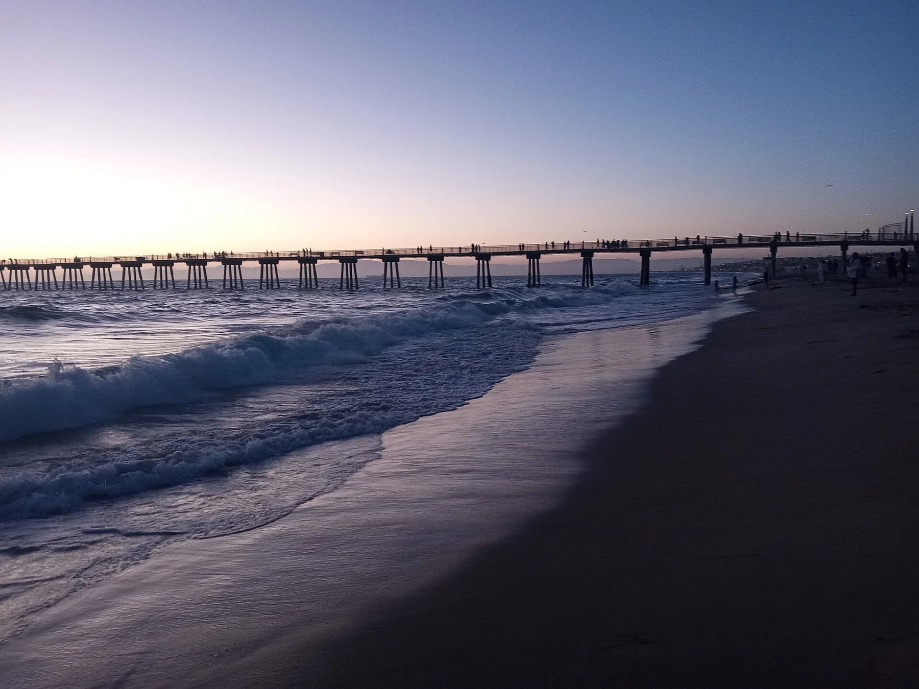 Hermosa Beach Pier silhouetted against a sunset sky.